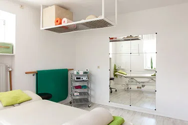 Behandlungsraum mit Therapieliege und physiotherapeutischen Geräten